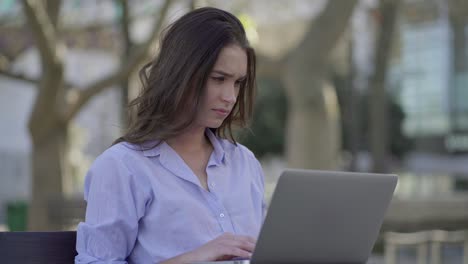 Pretty-Caucasian-woman-sitting-in-park,-working-on-laptop
